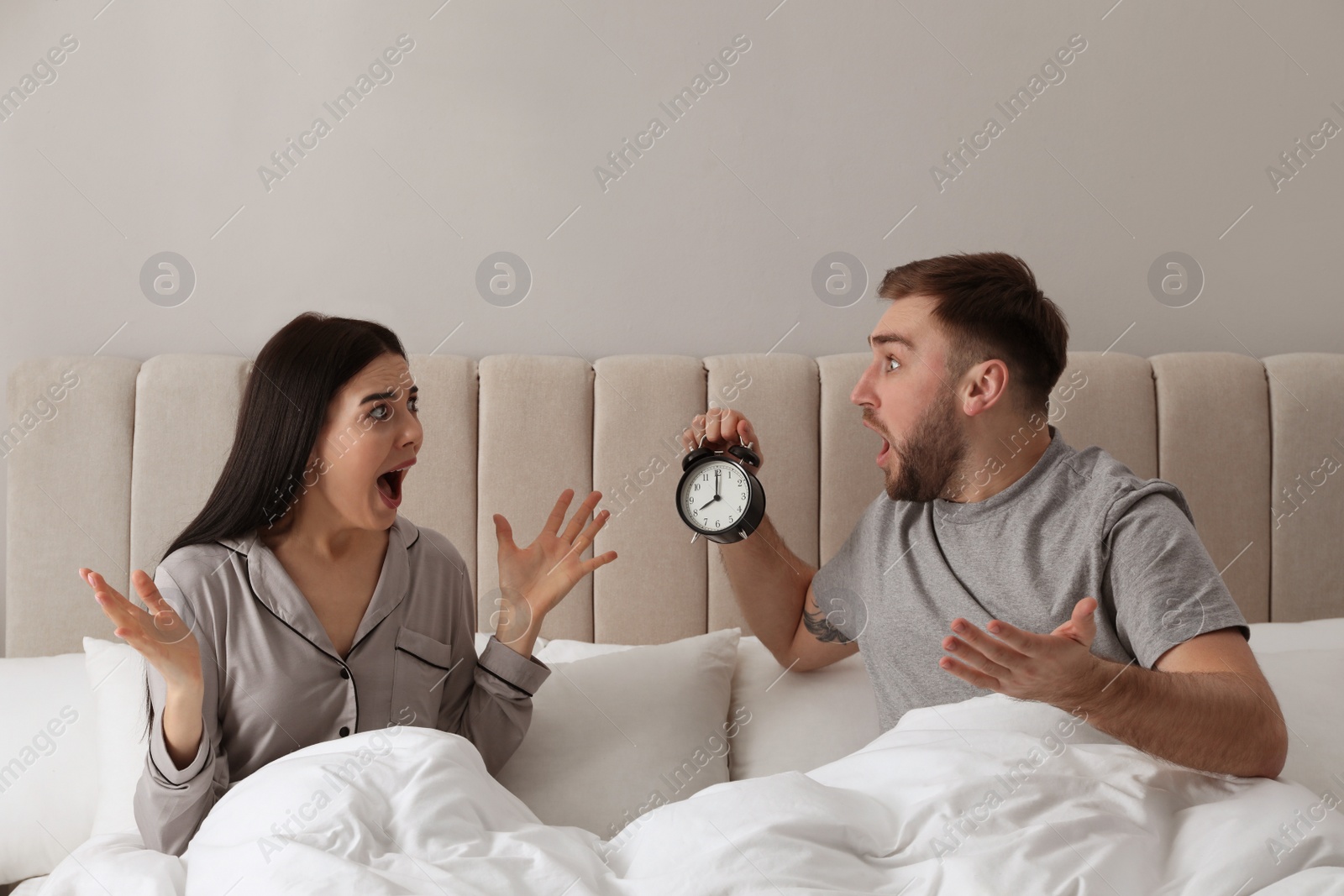 Photo of Emotional overslept couple in bed. Being late concept