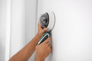 Technician installing CCTV camera on wall, closeup