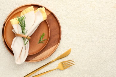 Photo of Stylish setting with cutlery, napkin, rosemary and plates on light textured table, flat lay. Space for text