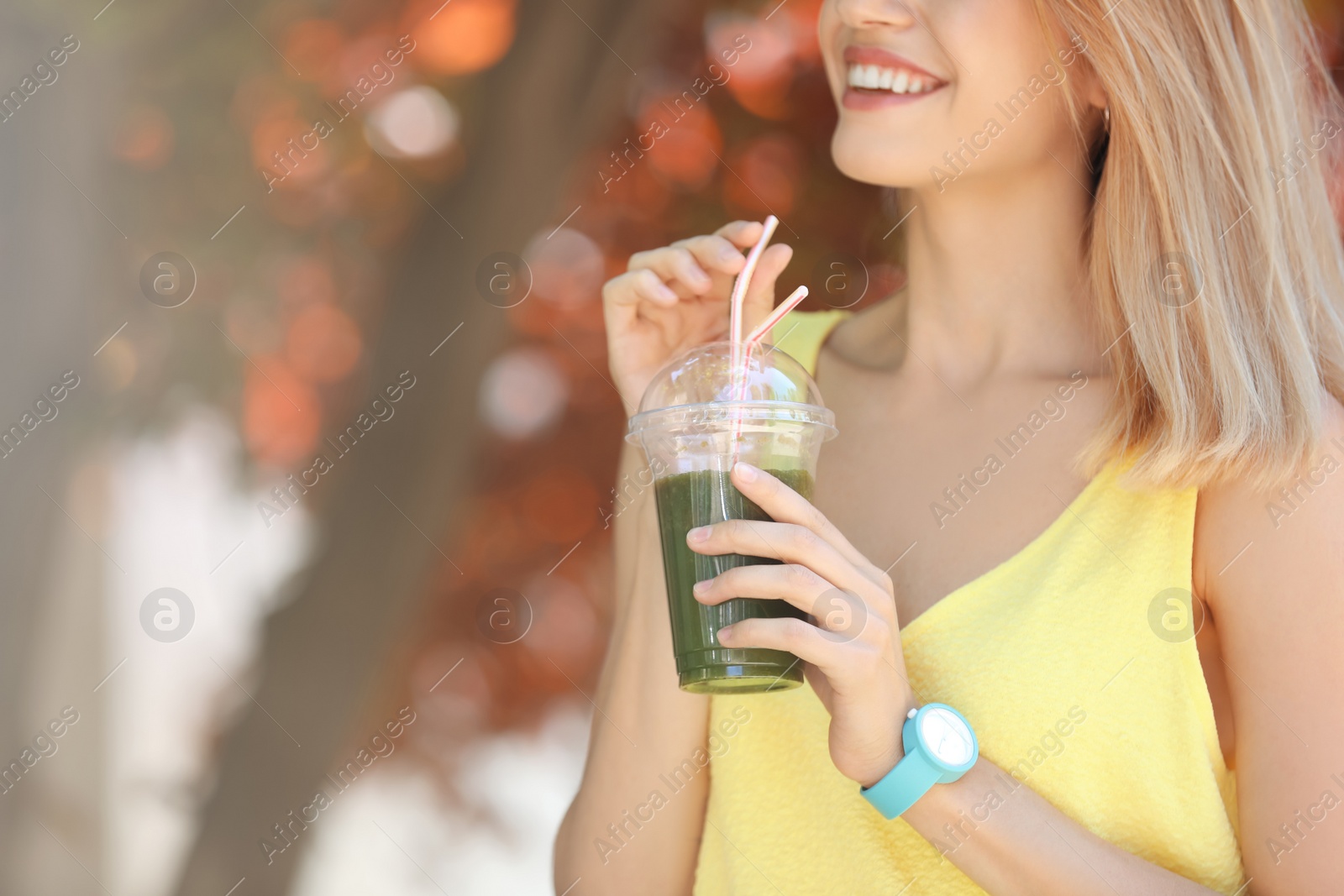 Photo of Young woman with plastic cup of healthy smoothie outdoors