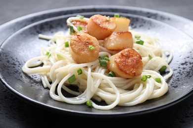 Photo of Delicious scallop pasta with green onion on table, closeup