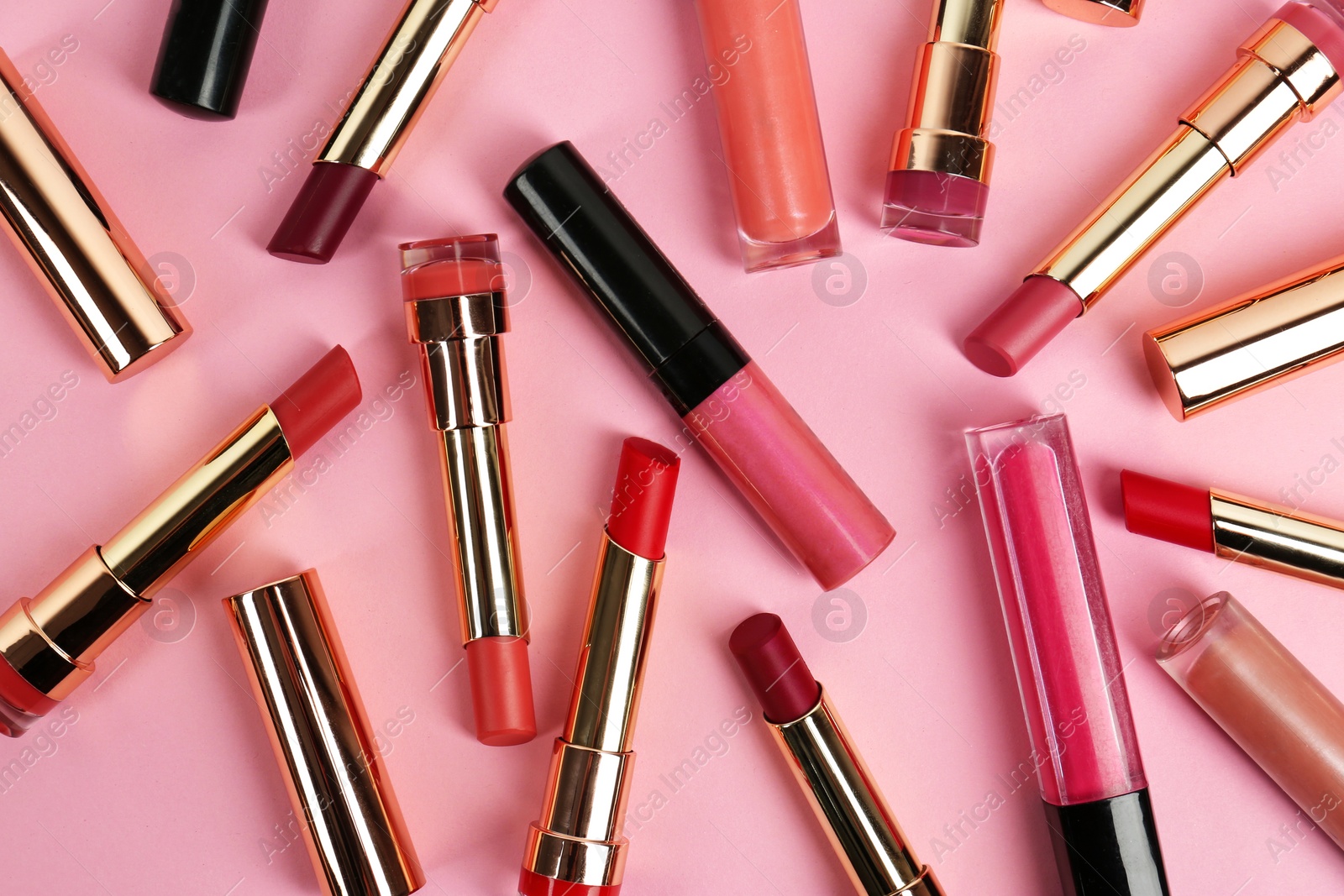 Photo of Set of bright lipsticks on pink background, flat lay