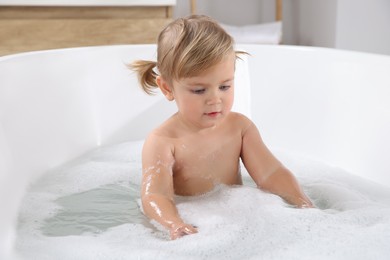 Cute little girl taking foamy bath at home
