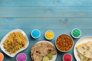 Photo of Traditional Indian food and color powders on light blue wooden table, flat lay with space for text. Holi festival celebration