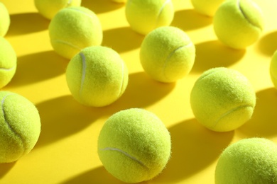 Photo of Tennis balls on yellow background, closeup. Sports equipment