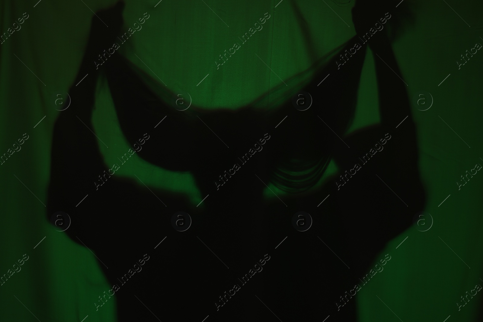 Photo of Silhouette of creepy ghost behind dark green cloth