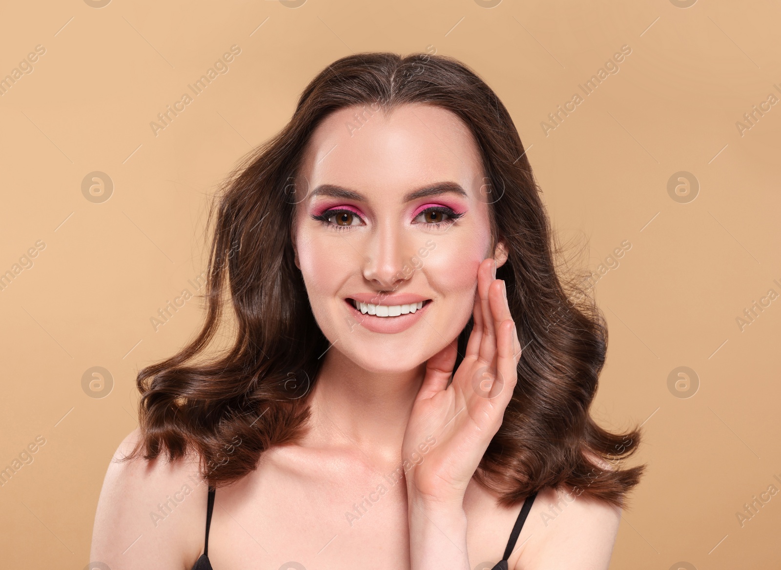 Photo of Portrait of beautiful young woman with makeup and gorgeous hair styling on beige background