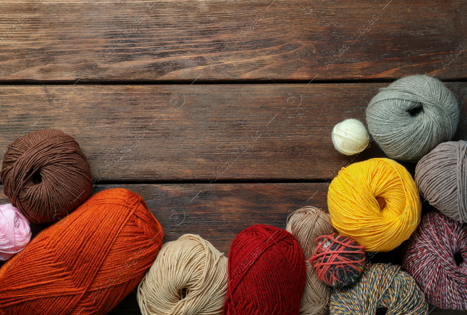 Photo of Soft woolen yarns on wooden table, flat lay. Space for text