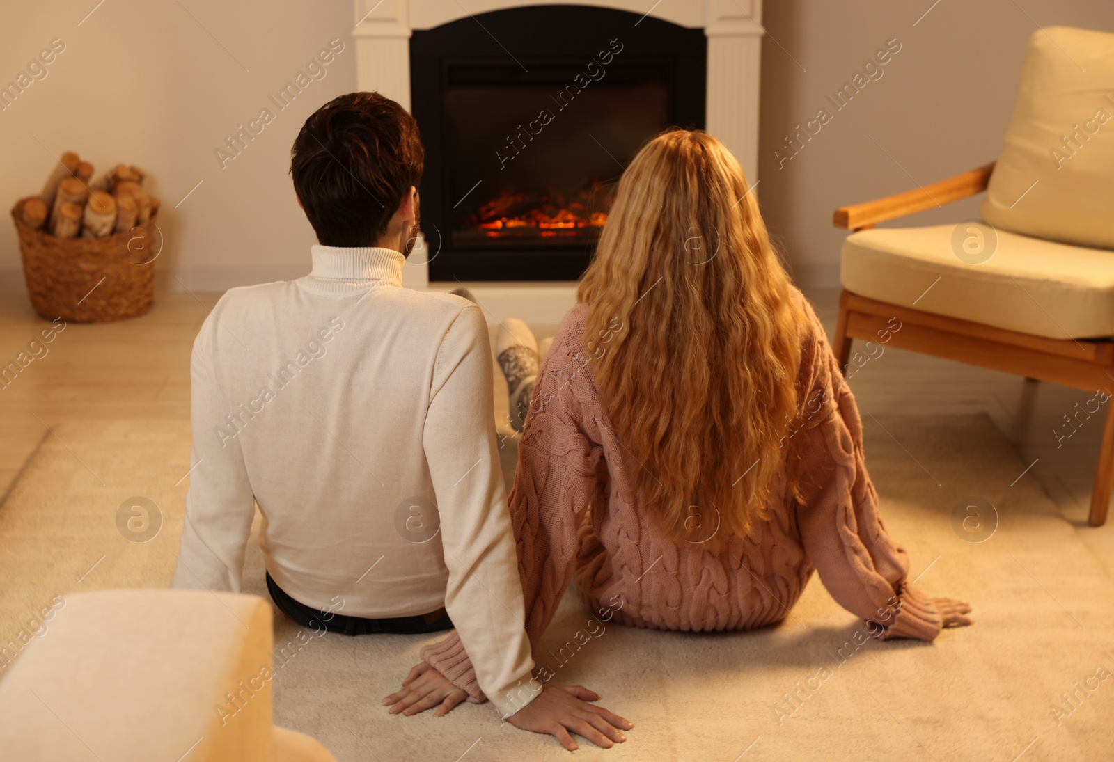 Photo of Lovely couple spending time together near fireplace at home, back view