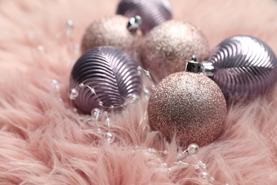 Photo of Beautiful Christmas baubles on pink faux fur, closeup
