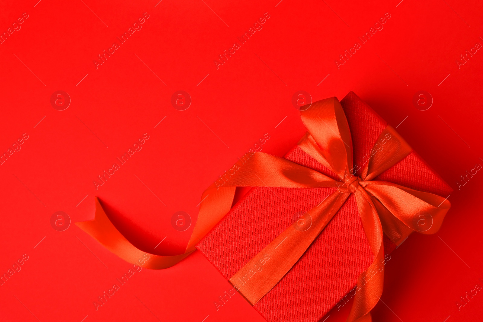 Photo of Beautiful gift box with bow on red background, top view. Space for text