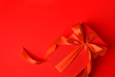 Photo of Beautiful gift box with bow on red background, top view. Space for text