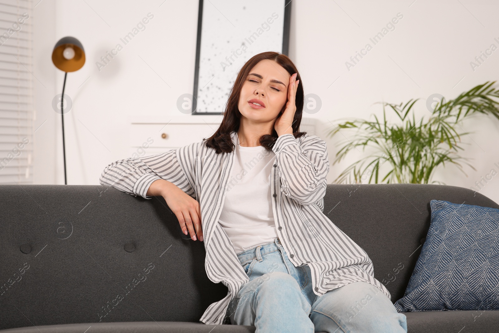 Photo of Young woman suffering from headache indoors. Hormonal disorders