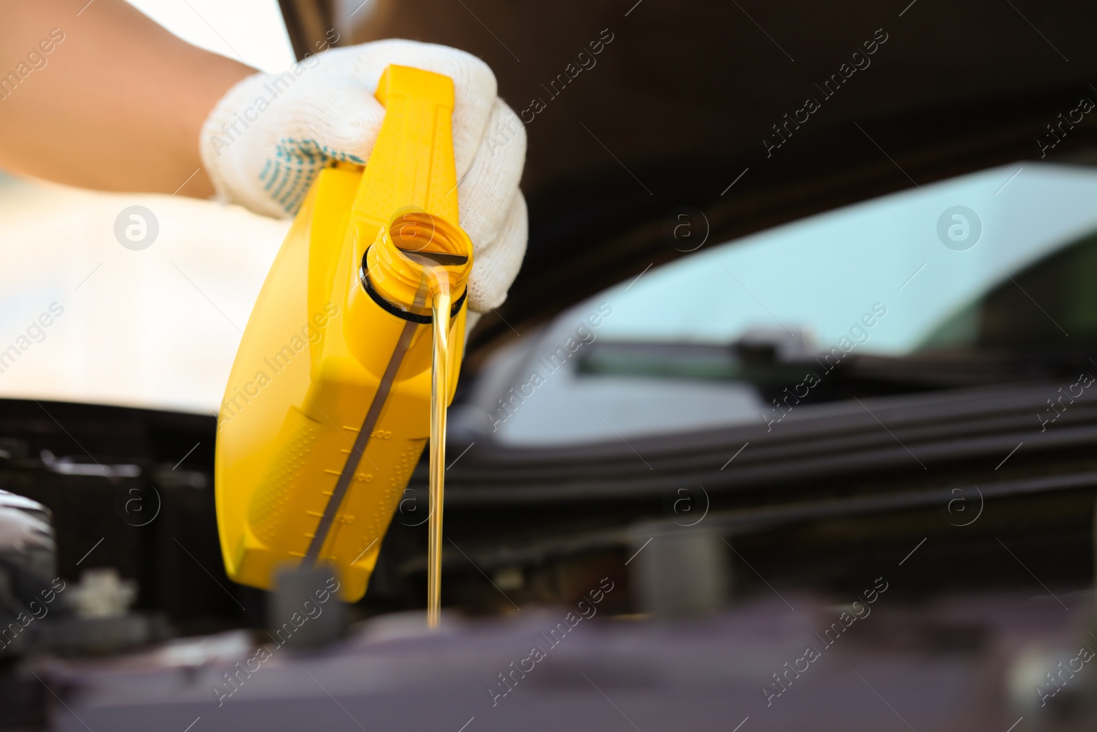 Photo of Man pouring motor oil from yellow container, closeup. Space for text