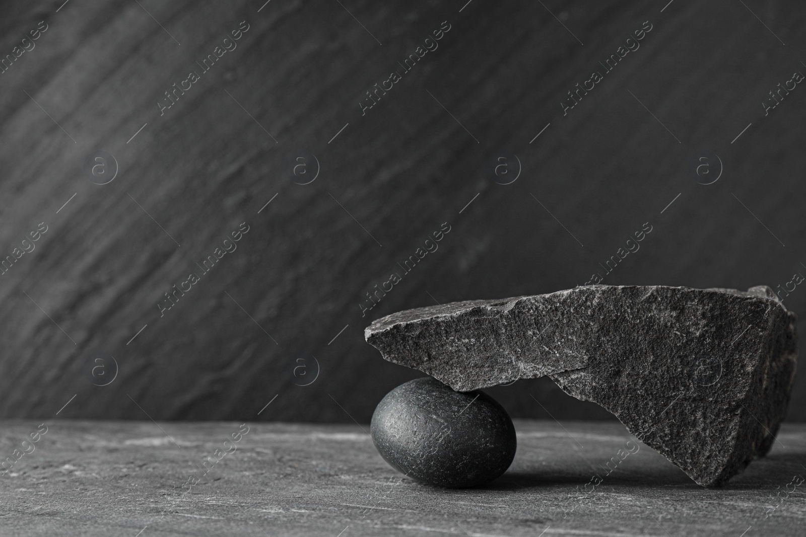 Photo of Presentation for product. Podium made of different stones on grey textured background. Space for text