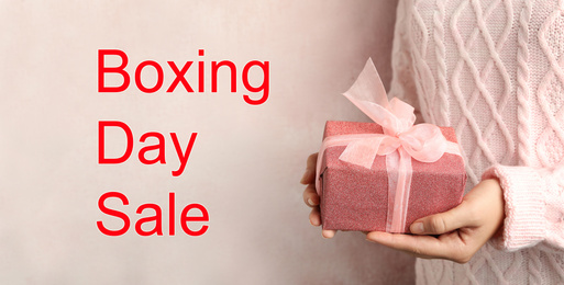 Boxing day sale. Woman with gift on light background, banner design