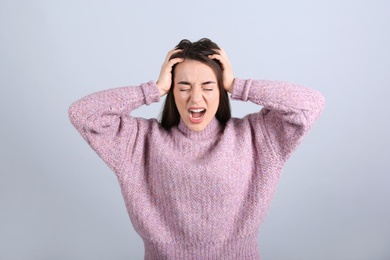 Portrait of stressed young woman on grey background