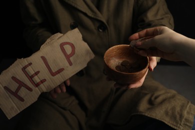 Photo of Woman giving coins to homeless with help sign, closeup. Charity and donation