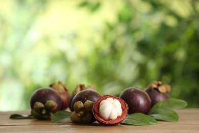 Photo of Delicious ripe mangosteen fruits on wooden table outdoors, space for text