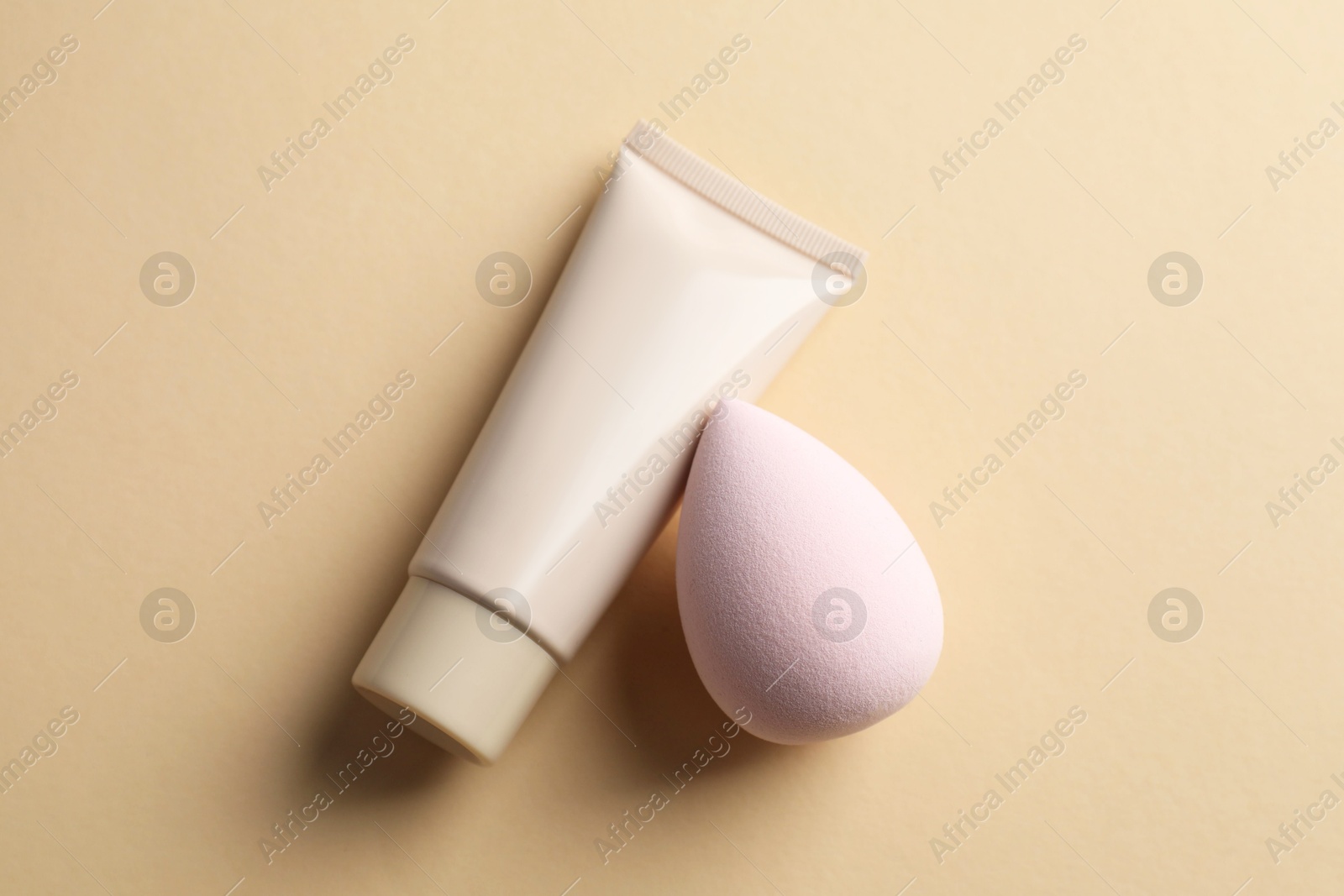 Photo of Makeup sponges and skin foundation on beige background, top view