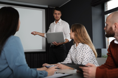 Business people listening to speaker in conference room with video projection screen