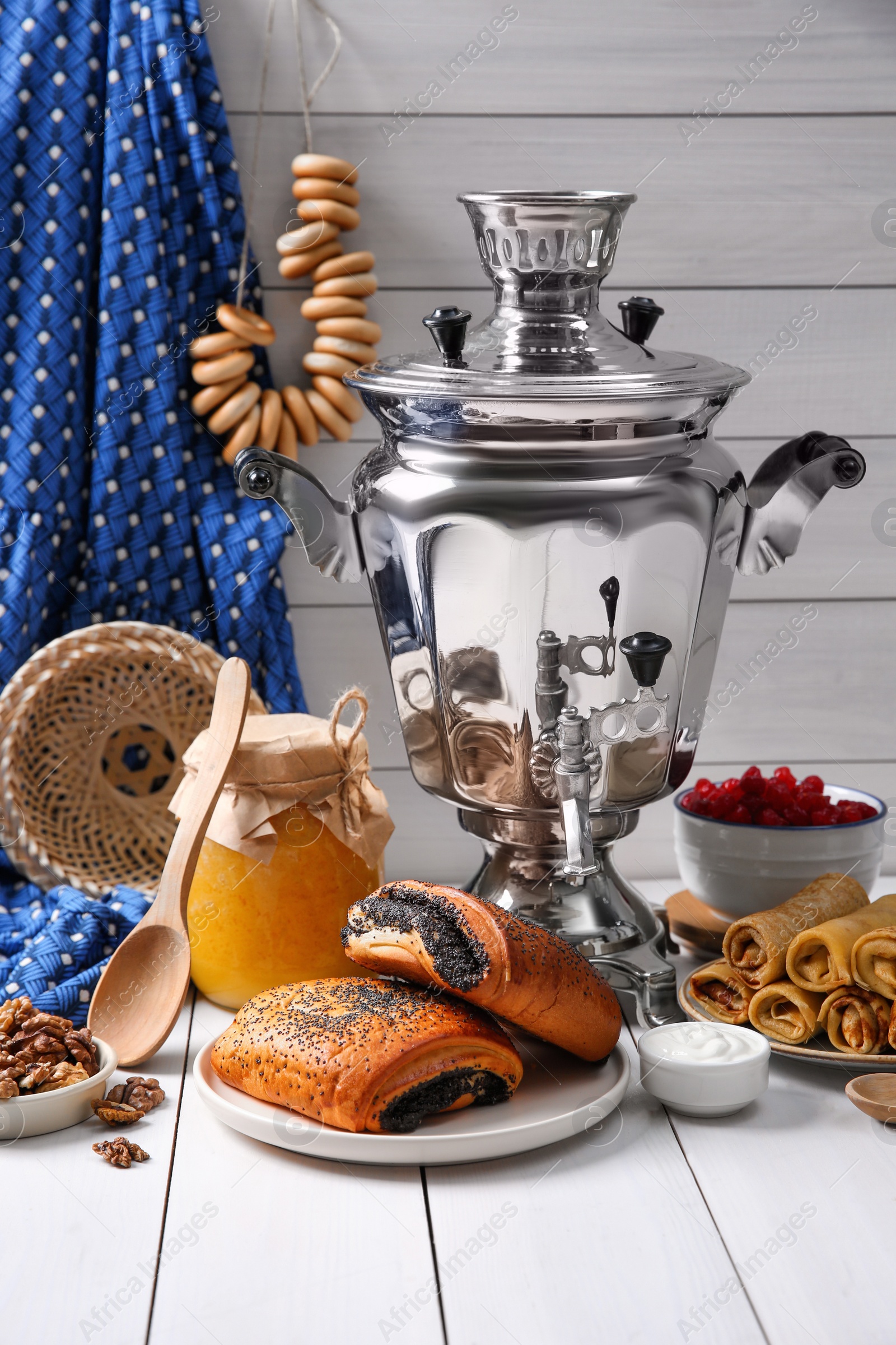 Photo of Traditional Russian samovar and treats on white wooden table