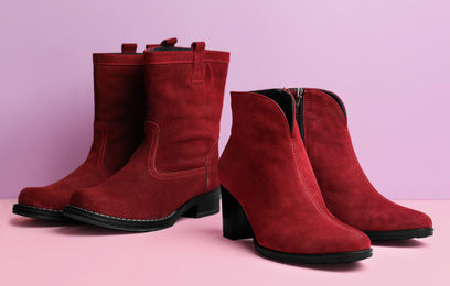 Photo of Stylish red female boots on color background