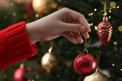 Photo of Woman holding red ball near Christmas tree, closeup