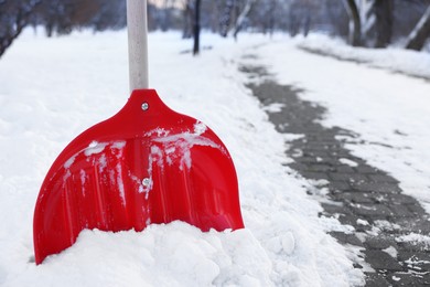 Snow shovel with wooden handle near sidewalk outdoors, closeup. Space for text