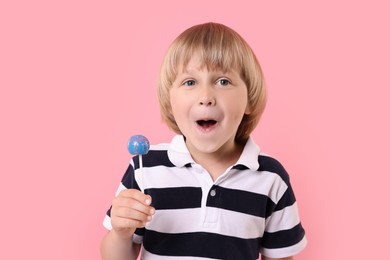 Emotional little boy with lollipop on pink background