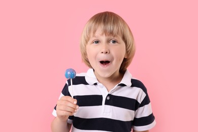 Photo of Emotional little boy with lollipop on pink background