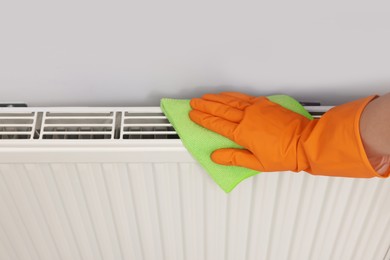 Photo of Woman cleaning radiator with rag indoors, above view