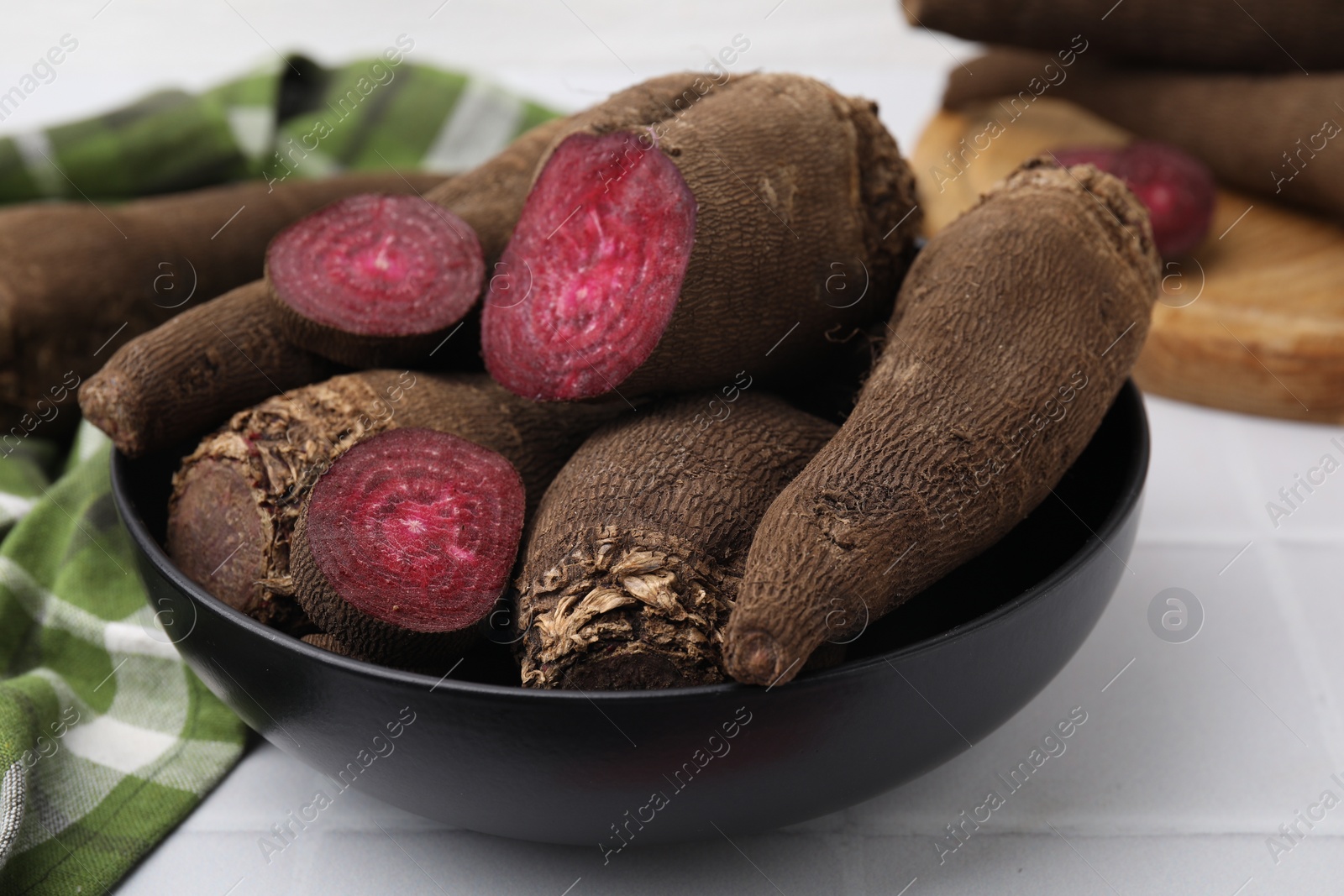 Photo of Whole and cut red beets in bowl on table, closeup