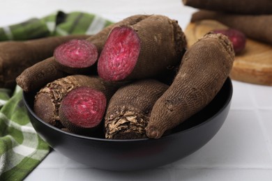 Whole and cut red beets in bowl on table, closeup