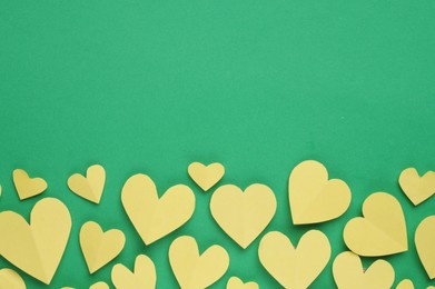 Paper hearts on green background, flat lay. Space for text