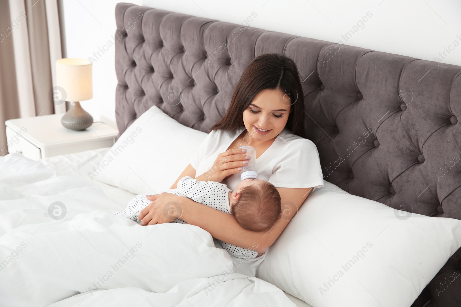 Photo of Woman feeding her baby from bottle on bed