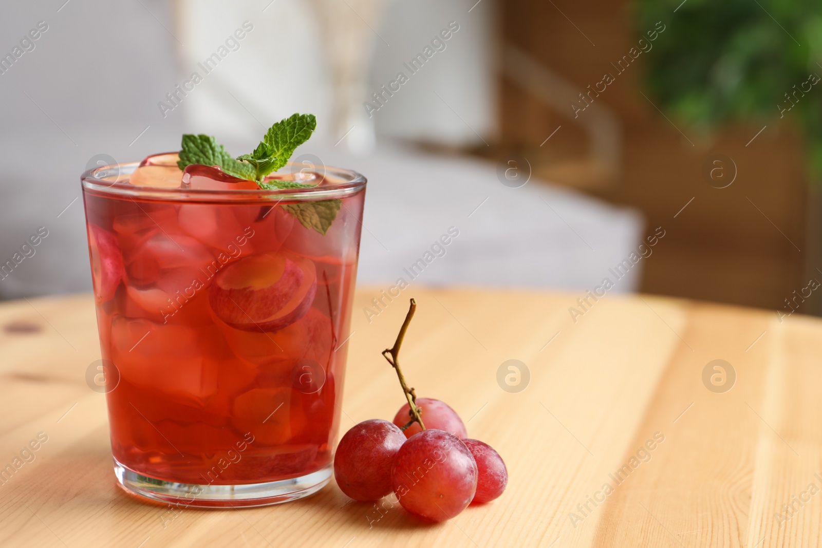 Photo of Refreshing drink with soda water, grapes, ice and mint on wooden table indoors. Space for text