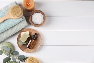 Flat lay composition with different spa products and burning candle on white wooden table. Space for text