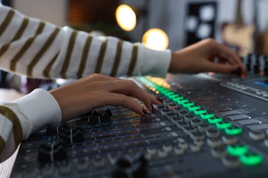 Photo of Woman working with professional mixing console in modern radio studio, closeup