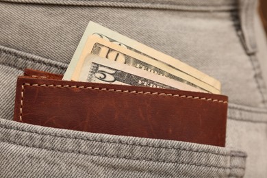 Photo of Wallet with dollar banknotes in pocket of grey jeans, closeup. Spending money
