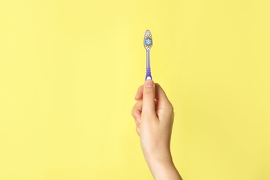 Photo of Woman holding manual toothbrush against color background