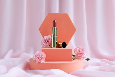 Photo of Stylish presentation of lipstick and roses on pink fabric