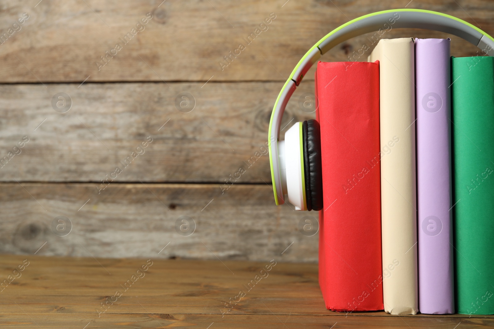 Photo of Books and modern headphones on wooden table, closeup. Space for text