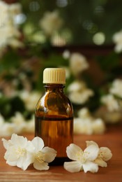 Photo of Bottle of jasmine essential oil and beautiful flowers on wooden table