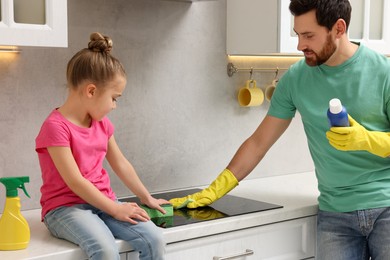 Photo of Spring cleaning. Father and daughter tidying up stove in kitchen together