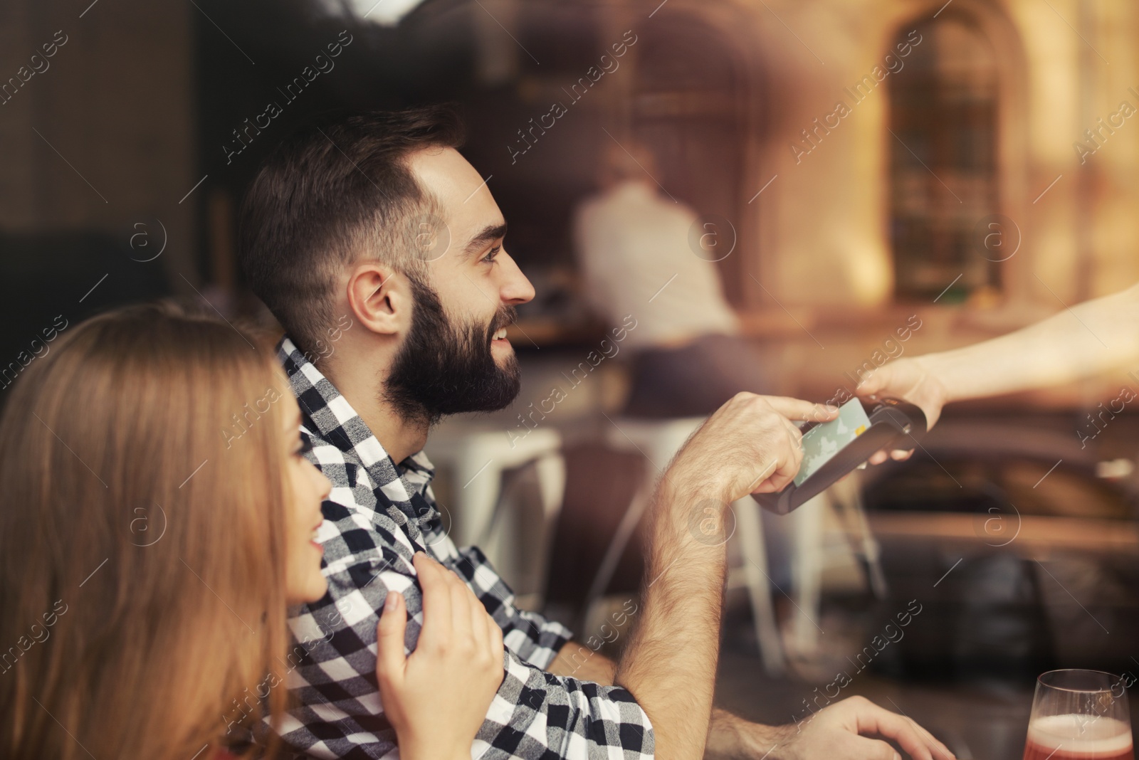 Photo of Man with credit card using payment terminal at restaurant, view through window