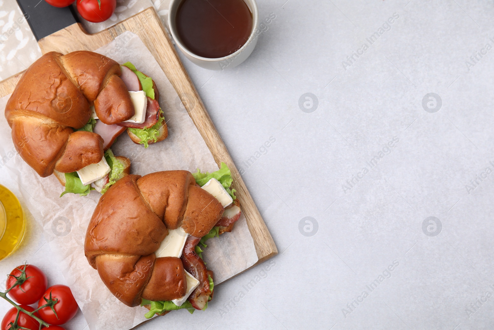 Photo of Tasty crescent rolls with brie cheese, ham and bacon on white table, flat lay. Space for text