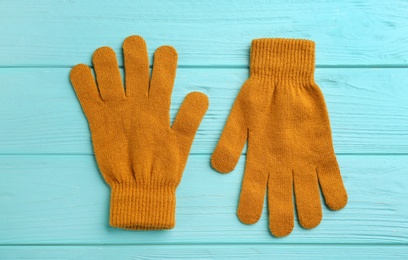 Stylish gloves on turquoise wooden background, flat lay