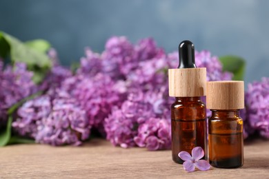 Photo of Cosmetic products and lilac flowers on wooden table, space for text