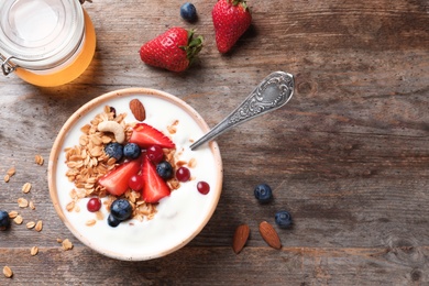 Tasty breakfast with yogurt, berries and granola on wooden table, top view